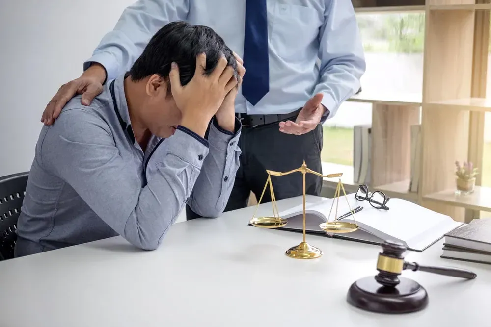 Attorney consoling a worried male client at his desk
