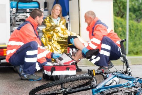 Injured female cyclist being treated by EMS at bicycle accident scene